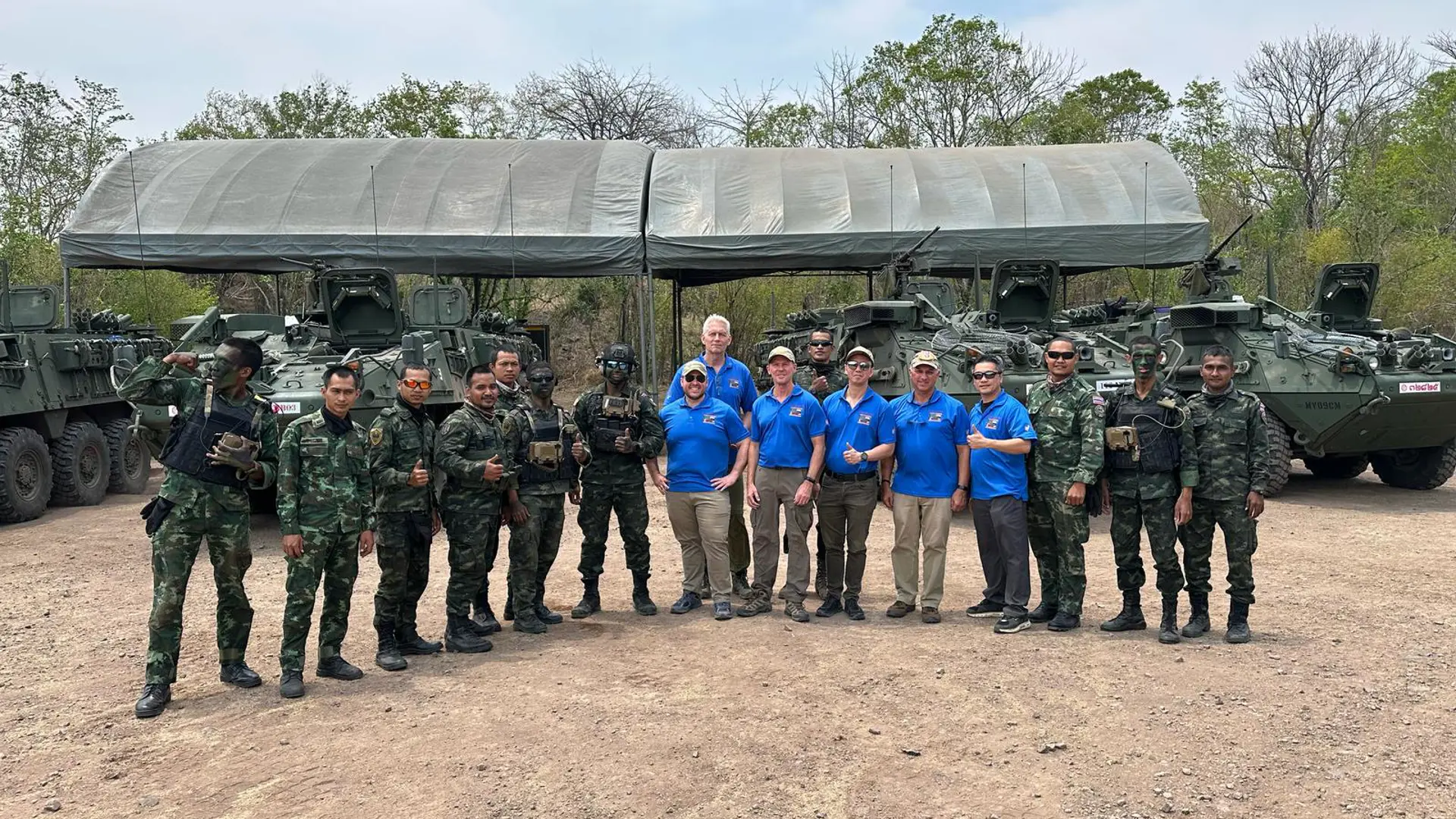 Systematic staff and Royal Thai Army soldiers pose together in front of armored vehicles during the Hanuman Guardian 25 military exercise.
